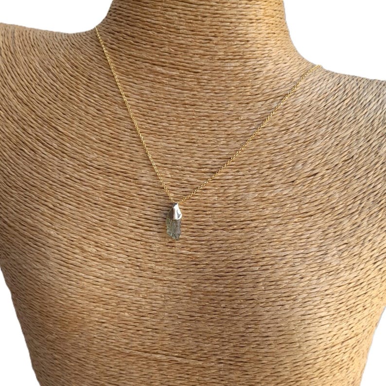 May include: A gold chain necklace with a green and silver crystal pendant.