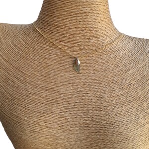 May include: A gold chain necklace with a small, green, raw crystal pendant.