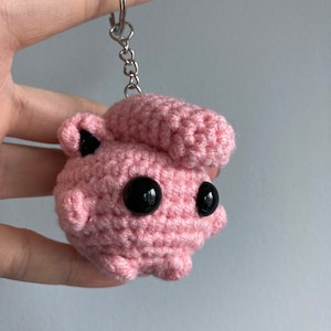 May include: Pink crocheted keychain with black eyes and a silver chain.