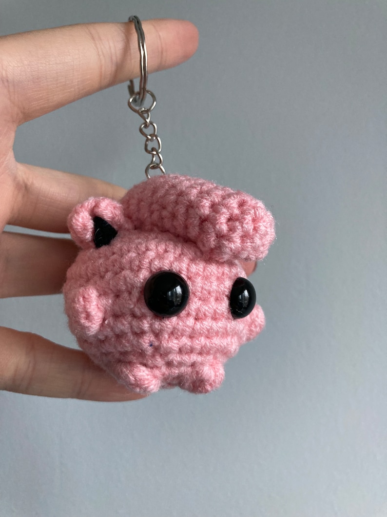May include: Pink crocheted keychain with black eyes and a silver chain.