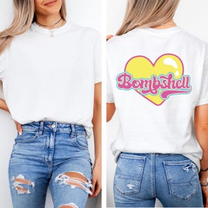 K&ouml;nnte beinhalten: Ein wei&szlig;es kurz&auml;rmeliges T-Shirt kombiniert mit einer blauen, zerrissenen Jeans. Die Vorderseite des T-Shirts ist schlicht wei&szlig;, w&auml;hrend die R&uuml;ckseite eine gro&szlig;e gelbe Herzgrafik mit pinkfarbenem und t&uuml;rkisfarbenem Rand und dem Wort Bombshell zeigt.