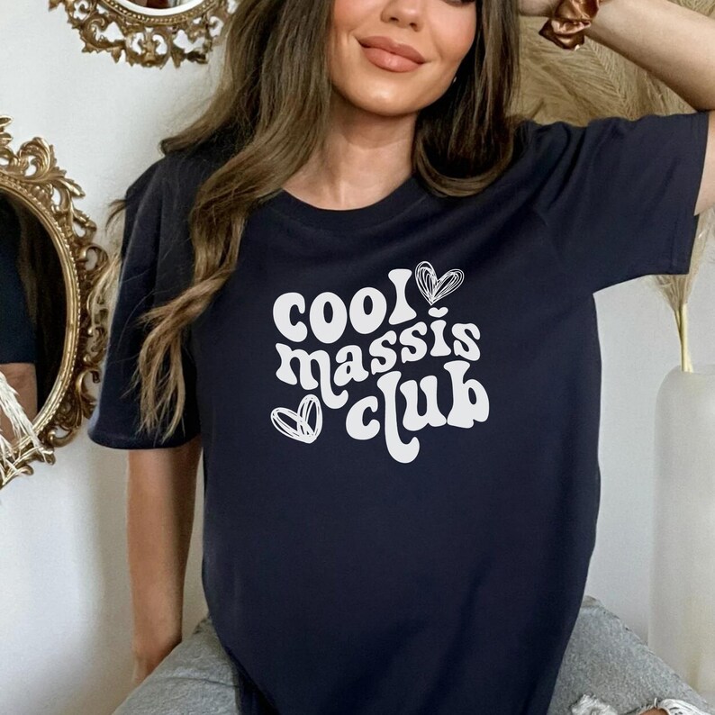 May include: A navy blue t-shirt with a white graphic that says "Cool Massis Club" in a retro font with hearts.