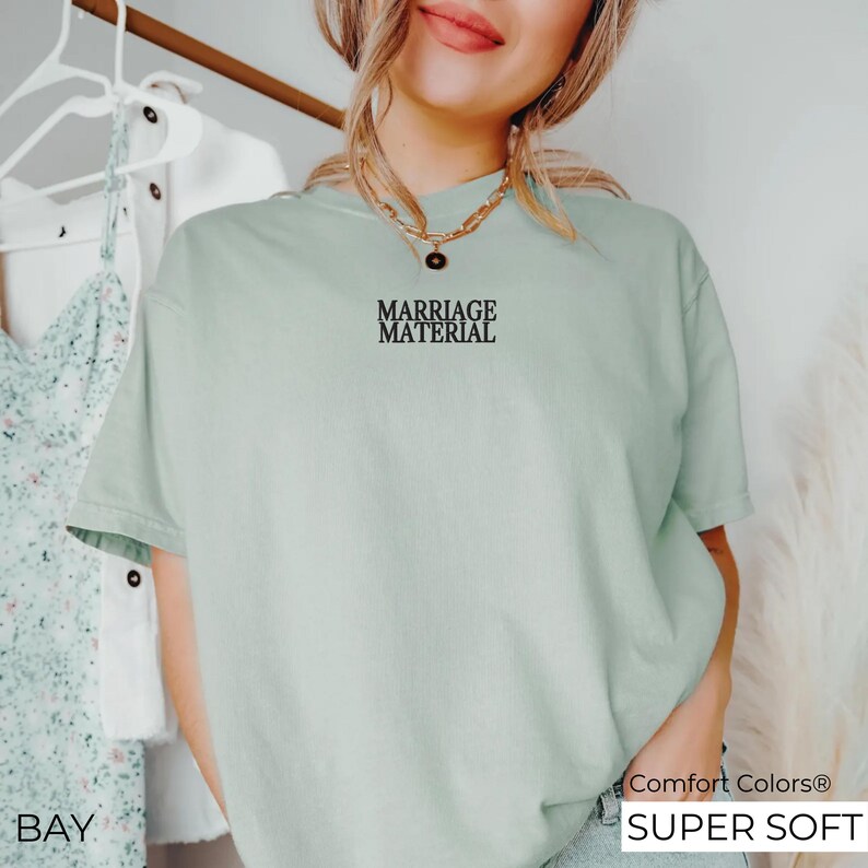 Puede incluir: Una camiseta verde claro con el texto "Marriage Material" impreso en la parte delantera. La camiseta est&aacute; hecha de una tela suave y c&oacute;moda y tiene un corte holgado.