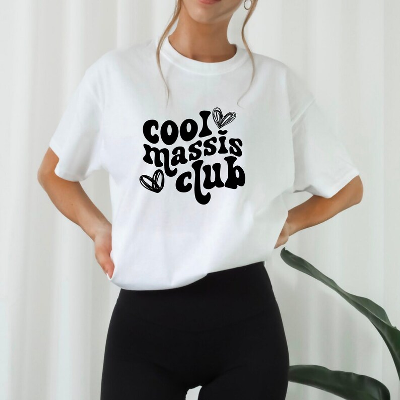 May include: White t-shirt with black text that reads "cool I &hearts; massis club" in a retro font. The text is centred on the shirt and is surrounded by two small hearts.