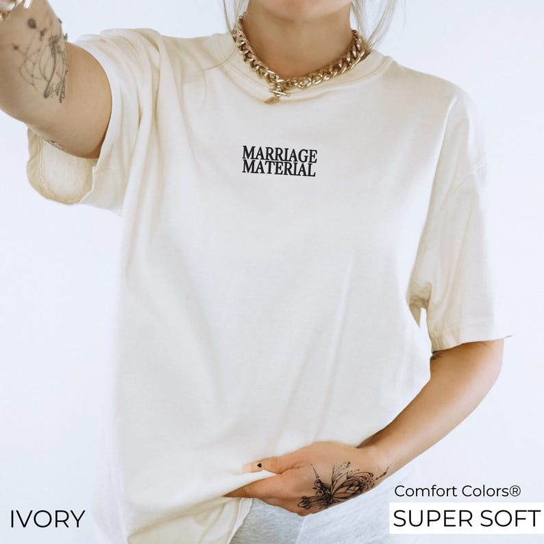Puede incluir: Camiseta de color marfil con el texto "Marriage Material" impreso en la parte delantera. La camiseta est&aacute; hecha de una tela suave y c&oacute;moda y tiene un corte holgado.