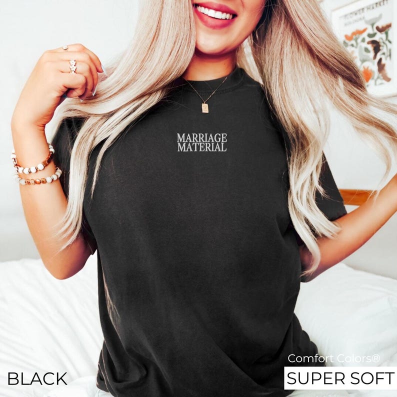 Puede incluir: Una camiseta negra con el texto "Marriage Material" impreso en la parte delantera. La camiseta es s&uacute;per suave y c&oacute;moda.
