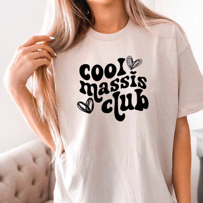 May include: A white t-shirt with black text that reads "cool massis club" with a heart design.