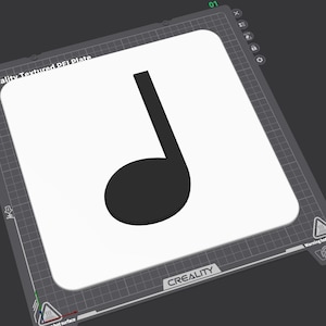 Peut inclure: Une plaque rectangulaire blanche avec un symbole de note de musique noir. La plaque est étiquetée "Creality Textured PEI Plate" et est posée sur une surface gris foncé. La plaque a un motif quadrillé sur les bords.