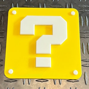 May include: A yellow square with a white question mark in the center. The question mark is made of blocks and has a pixelated look. The square has four white dots on the edges.