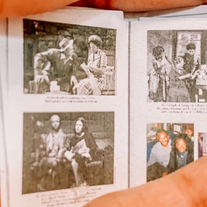 May include: A black and white photo album with several pictures of people. The album is open to a page with two photos. The top photo shows a group of people sitting at a table. The bottom photo shows two people sitting on a sofa.