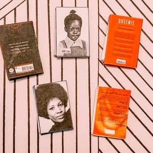 May include: Five paperback books with different covers. The books are on a striped background. The books are all different colours and have different titles. The titles are "They Killed My Mother", "Queenie", "How We Fight For Our Lives", and "The Hate U Give".
