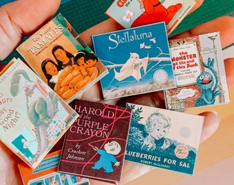 Könnte beinhalten: Eine Sammlung von Miniatur-Kinderbüchern, darunter "Too Many Tamales", "Clifford, der große rote Hund", "Stellaluna", "Harold und der lila Stift", "Blaubeeren für Sal", "Das Monster am Ende dieses Buches" und "Unsere Dinosaurier sagen Gute Nacht".