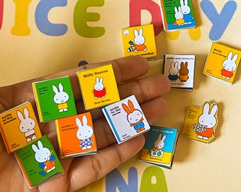 Könnte beinhalten: Eine Sammlung von zehn Miniatur-Kinderbüchern mit der Figur Miffy. Die Bücher haben farbenfrohe Umschläge mit Illustrationen von Miffy in verschiedenen Aktivitäten, wie Tanzen, Spielen im Schnee und Feiern ihres Geburtstages. Der Text auf den Umschlägen enthält Titel wie "Miffy tanzt", "Miffy im Schnee" und "Miffys Geburtstag".