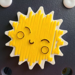 May include: A yellow sun with a white outline and a smiling face. The sun has a textured surface and is shaped like a star.