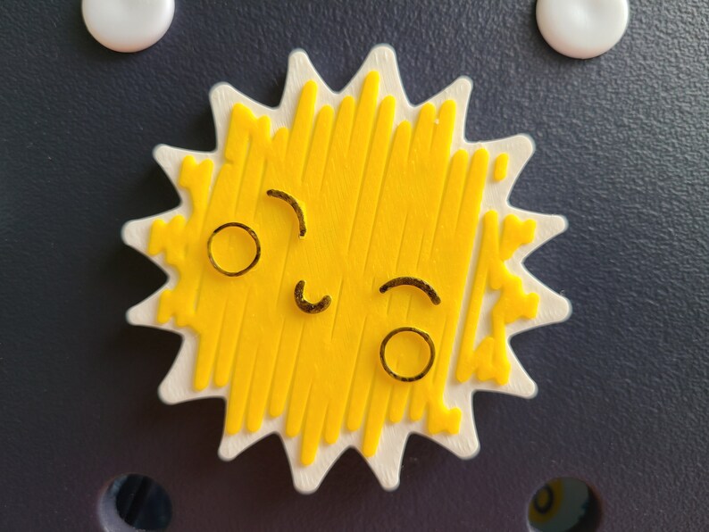 May include: A yellow sun with a white outline and a smiling face. The sun has a textured surface and is shaped like a star.
