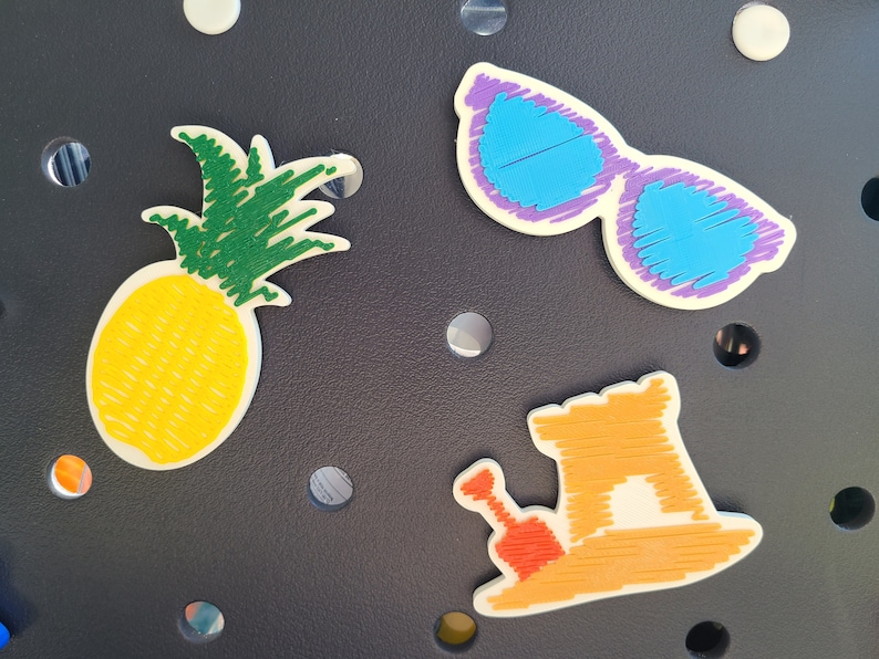May include: A set of four felt patches featuring a pineapple, sunglasses, a sandcastle, and a bucket and shovel. The patches are all white with colorful details.
