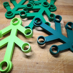 May include: A set of five green plastic candle holders in the shape of a tree. The candle holders are arranged in a cluster on a wooden surface.