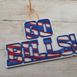 May include: A white, blue, and red 3D printed ornament with the words "GO BILLS!" in a striped pattern.