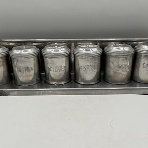 May include: A set of seven silver spice jars with labels for cinnamon, nutmeg, cloves, allspice, pepper, ginger, and a blank jar.