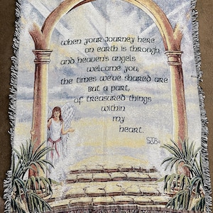 Puede incluir: Tapiz tejido con un &aacute;ngel, un arco y texto. El texto dice "when your journey here on earth is through and heaven's angels welcome you..." El tapiz tiene un borde con flecos y una paleta de colores suaves beige, marr&oacute;n y azul.