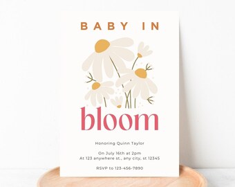 May include: A baby shower invitation with a floral design. The invitation says "Baby in Bloom" and includes the text "Honoring Quinn Taylor, On July 16th at 2pm, At 123 anywhere st., any city, st 12345, RSVP to 123-456-7890".