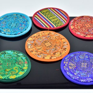 以下が含まれることがあります： 複雑な刺繍模様が施された丸い瞑想クッションが6つ。クッションは青、緑、オレンジ、赤、黄など様々な色で、幾何学模様と花柄が特徴です。