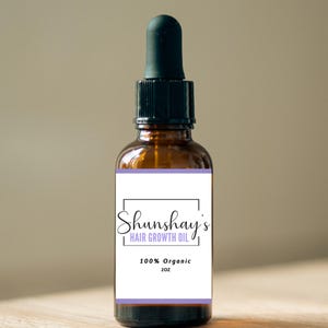 Op de afbeelding: Een bruine glazen fles met een druppelaar en een wit etiket. Het etiket zegt "Shunshay's Hair Growth Oil" en "100% Organic 2 oz."