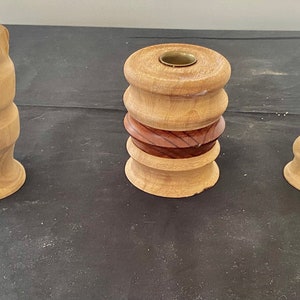 以下が含まれることがあります： 自然な木製の仕上げの、木製のキャンドルホルダーが3つあります。キャンドルホルダーはすべて形とサイズが異なりますが、すべて似たようなデザインです。キャンドルホルダーは、どんな家にも素朴な魅力を加えるのに最適です。