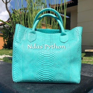 May include: A turquoise python leather tote bag with the text "Ndas Python" on the front.