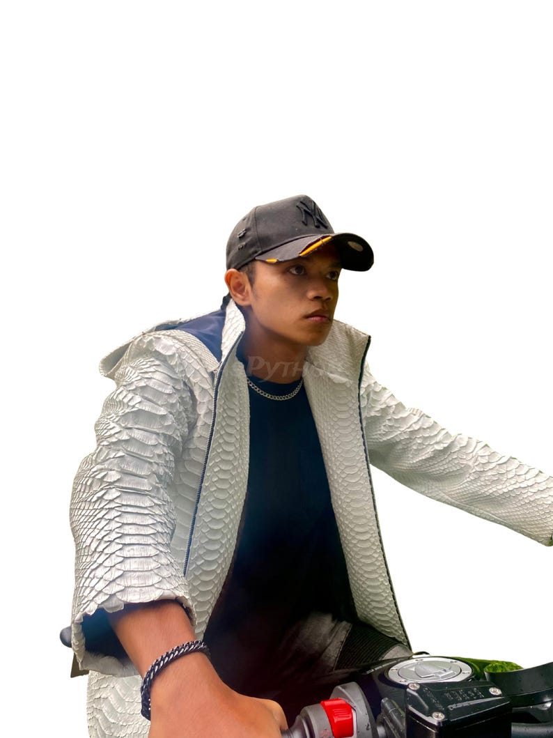 May include: A white textured jacket with black trim and a black baseball cap. The jacket features a scale-like pattern. The cap has a yellow brim and a logo. A silver chain necklace and bracelet are also visible.
