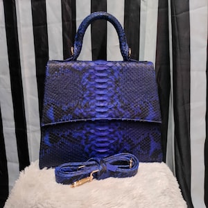May include: A blue python skin handbag with a top handle and a detachable shoulder strap. The bag has a flap closure and a textured snakeskin pattern.