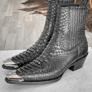 May include: A pair of black leather cowboy boots with a snakeskin pattern and silver toe caps.