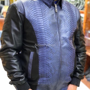 Puede incluir: Una chaqueta de cuero azul y negro con cierre de cremallera. La chaqueta está hecha de piel de pitón y tiene un diseño único.