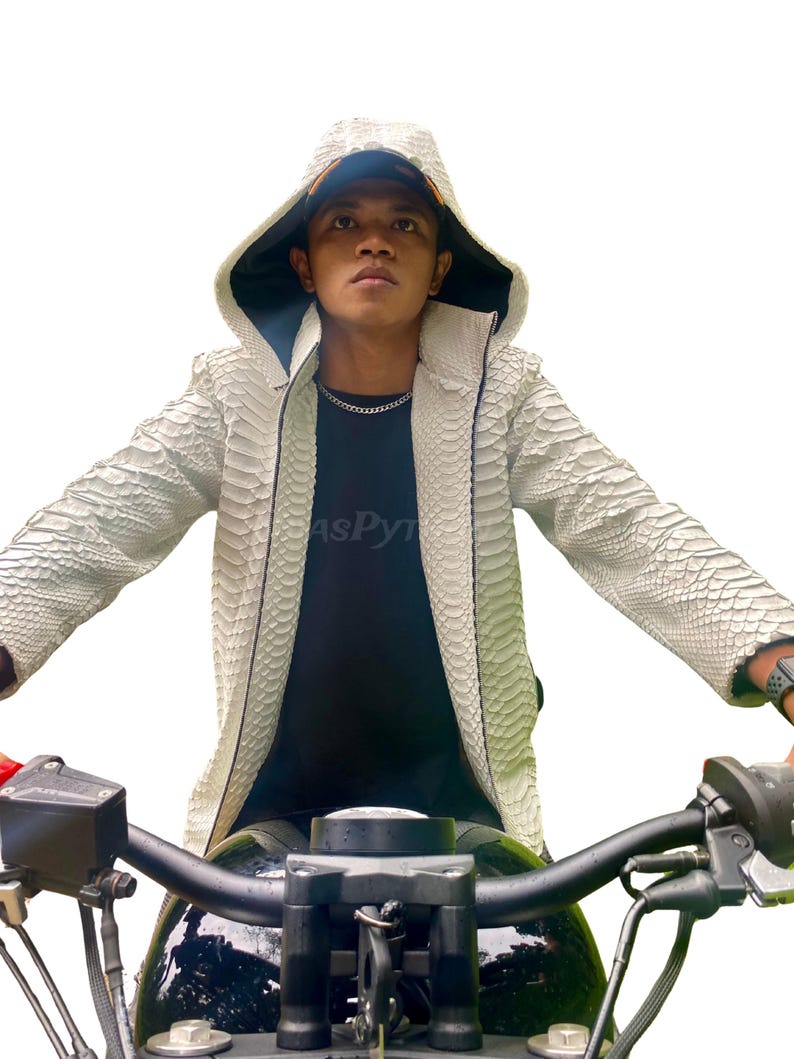 May include: A white snakeskin-patterned jacket with a hood and zip closure. The jacket has a dark lining. The person in the image is wearing a black t-shirt and a silver chain. The jacket is the main focus of the image.