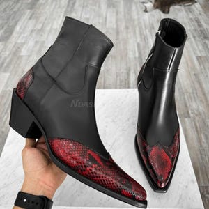 May include: Black leather cowboy boots with a pointed toe and a red and black snake print design.