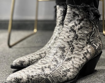 May include: A pair of pointed-toe ankle boots with a snakeskin pattern. The boots have a black heel and a black sole.