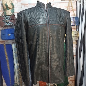 以下が含まれることがあります： ヘビ柄の黒い革のジャケット。赤いステッチが施され、ジッパーで閉めることができます。スタンドカラーです。