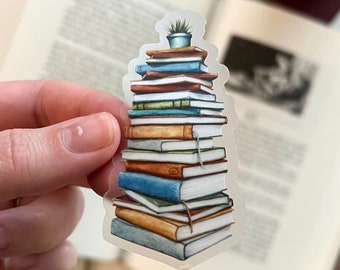 Puede incluir: Una pila de libros con una pequeña planta en maceta en la parte superior. Los libros son de varios colores y tamaños, y algunos tienen títulos visibles. La pegatina está sobre un fondo transparente.