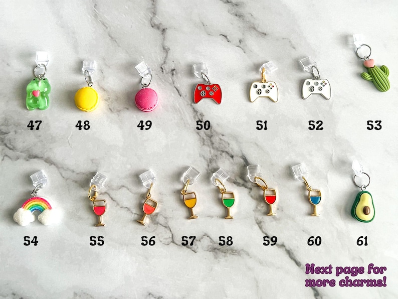 May include: A collection of 61 colorful charms, including a green frog, yellow macaron, pink macaron, red video game controller, white video game controller, rainbow, wine glass, avocado, and more. The charms are attached to clear plastic clips.