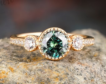 May include: A gold ring with a green gemstone surrounded by smaller diamonds. The ring is set on a gray rock.