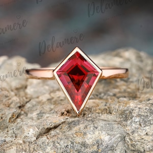 Op de afbeelding: Een ring van roségoud met een rode, vierkante edelsteen gezet in een diamantvormige zetting.