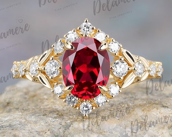 May include: A gold ring featuring a large oval ruby gemstone surrounded by smaller diamonds. The ring has a delicate floral design on the band.