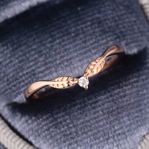 May include: A delicate rose gold ring featuring a small diamond and leaf details. The ring is designed to be worn as a wedding band or promise ring.
