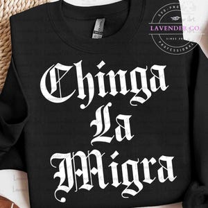 May include: Black sweatshirt with the phrase "Chinga La Migra" in white gothic lettering. The sweatshirt also features a small logo from "Lavender Co." in the upper right corner.