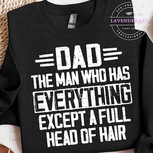 May include: Black sweatshirt with white text that reads "DAD THE MAN WHO HAS EVERYTHING EXCEPT A FULL HEAD OF HAIR." The design includes the Lavender Co. logo in the upper right corner.