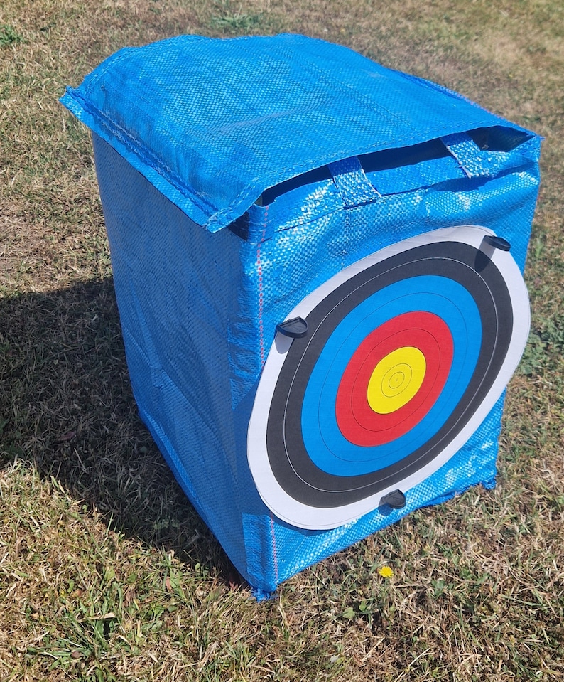 May include: Blue archery target bag with a white and black archery target with red, yellow, and blue rings.