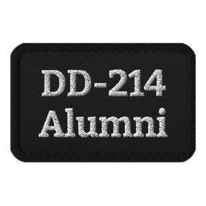 Puede incluir: Parche rectangular negro con texto bordado blanco "DD-214 Alumni". El parche tiene un borde cosido. El texto está en negrita, fuente sans-serif.