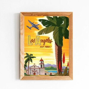 Pode incluir: Pôster de viagem vintage que anuncia uma viagem para Los Angeles, Califórnia. O pôster apresenta um avião voando sobre uma palmeira e um prédio branco com telhado vermelho. O texto do pôster diz "Los Angeles Fly TWA!"