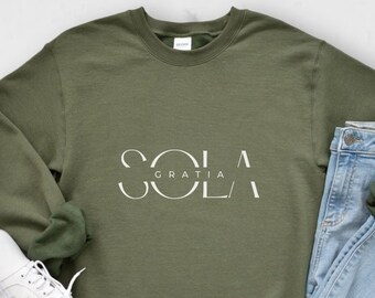 May include: A green sweatshirt with the text "Sola Gratia" in white lettering.