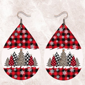 May include: A pair of teardrop-shaped earrings with a Christmas theme. The top portion features a red and black buffalo plaid pattern with white snowflakes. The bottom has a white background with Christmas trees, including a leopard print tree.